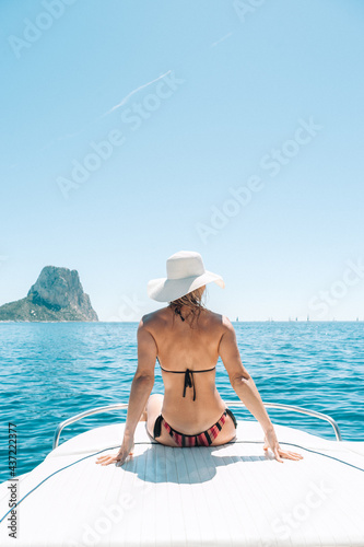 Blond haired woman sitting on boat deck at the mediterranean sea