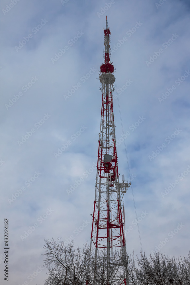A 4g cell tower against a background of cloudy sky and bare branches