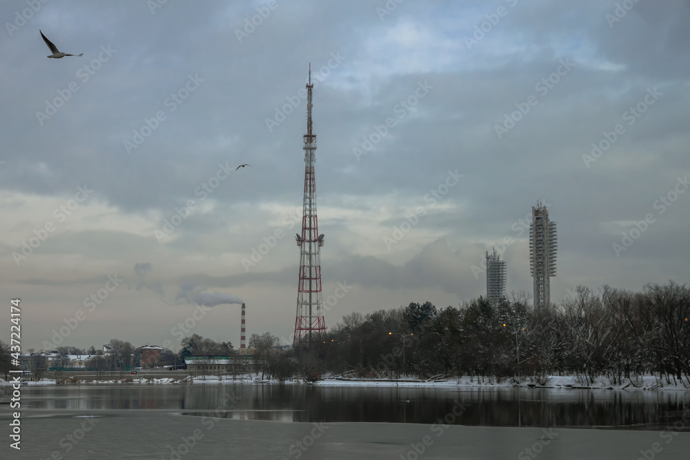 On the shore of the lake with ice is a cell tower. The stadium's floodlights and the CHPP pipe are visible