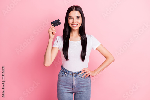 Portrait of attractive cheerful girl holding in hands atm card web transfer payment isolated over pink pastel color background