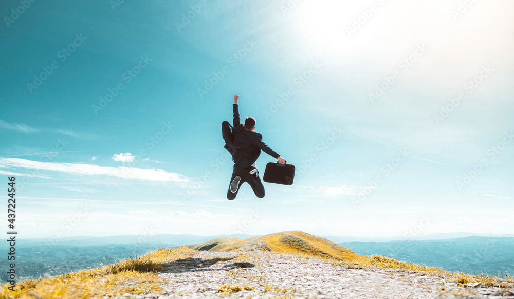 Excited young businessman jumping keeping arms raised hiking the mountain peak - Celebrating success, winner and leader concept - obrazy, fototapety, plakaty 