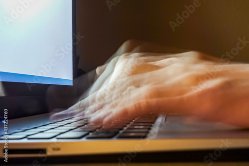 Schnell tippende Hände an einem Laptop Keyboard. Homeoffice zur späten Stunde im Arbeitszimmer. Screentime in der Nacht. Blurry ghost effect. Nachtarbeit am heimischen PC, Dienstort ist zu Hause.
