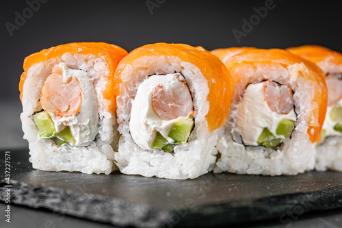 appetizing sushi roll philadelphia with shrimp cheese cucumber and salmon on a black stone plate