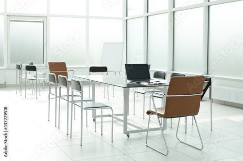 Flipchart laptop chairs glass table in a bright office space