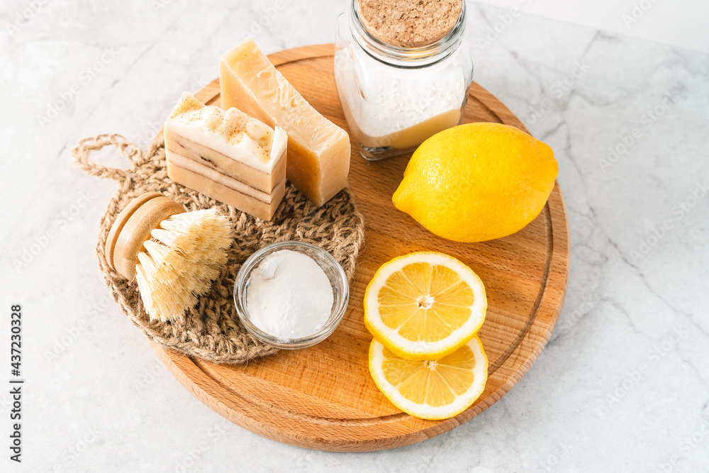 Eco friendly natural cleaners, jar with baking soda, dish brush, lemon, soap on white marble table background. Organic ingredients for homemade cleaning. Zero waste concept. Eco friendly natural cleaners, jar with baking soda, dish brush, lemon, soap on white marble table background. Organic ingredients for homemade cleaning. Zero waste concept.
