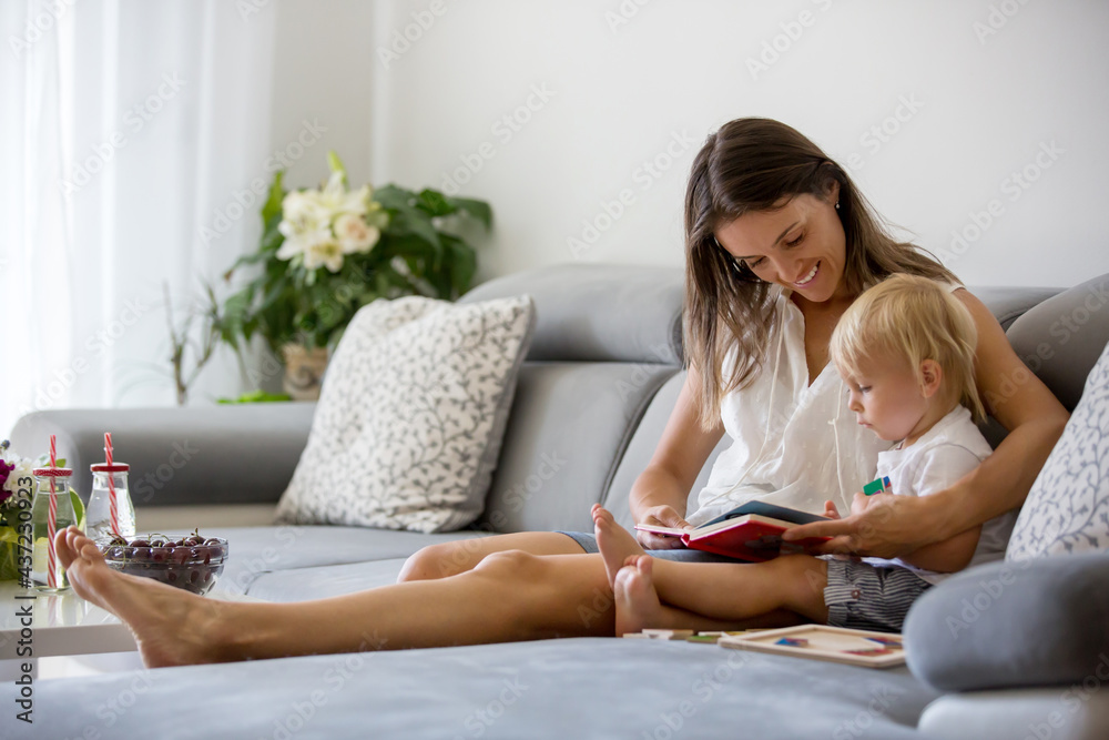 Charming mother, making puzzle with her cute toddler baby boy at home