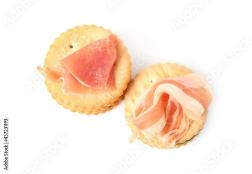 Delicious crackers with prosciutto on white background, top view