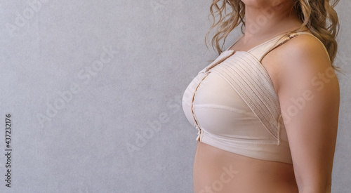 Young woman in beige compression bra bandage after breast augmentation  surgery mammoplasty. banner. advertising. copy space Stock Photo