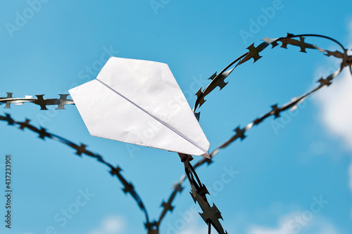 Bilde på lerret Paper plane stuck in barbed wire against blue sky