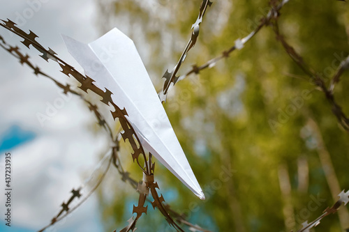 Tablou pe pânză Paper plane stuck in barbed wire