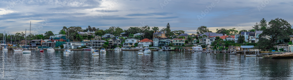 View of residential properties on Sydney harbour foreshore and sail boats yachts moored in the Bay NSW Australia  