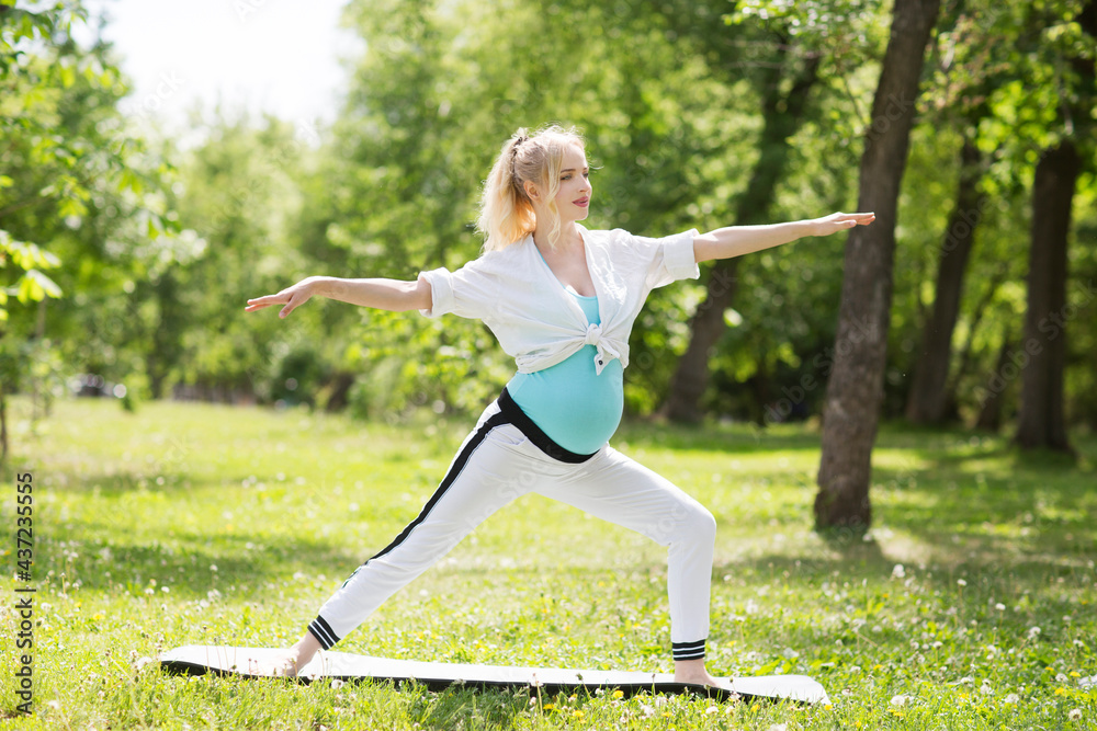 young pregnant woman doing stretching and yoga in a park young pregnant woman doing stretching and yoga in a park