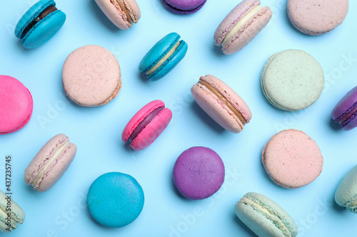 Delicious colorful macarons on light blue background, flat lay