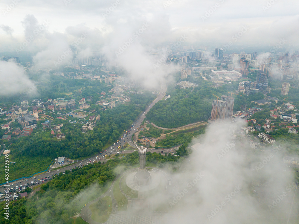 Motherland monument in Kiev between the clouds. Aerial drone view.