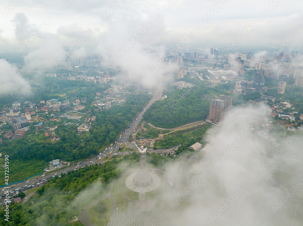Fototapeta premium Motherland monument in Kiev between the clouds. Aerial drone view.