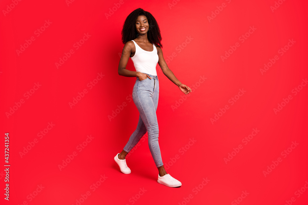 Full length body size view of lovely cheerful thin content girl going isolated over bright red color background Full length body size view of lovely cheerful thin content girl going isolated over bright red color background