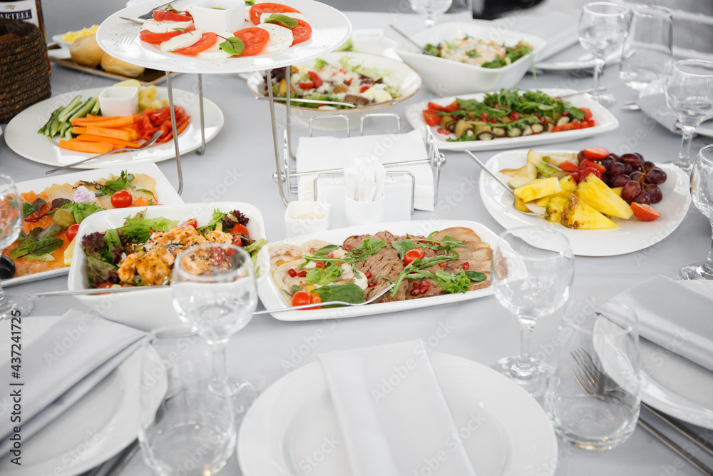 
Beautifully set table in the banquet hall of the restaurant. A table with appetizers for wine, cold dishes and salads. White tablecloths and napkins