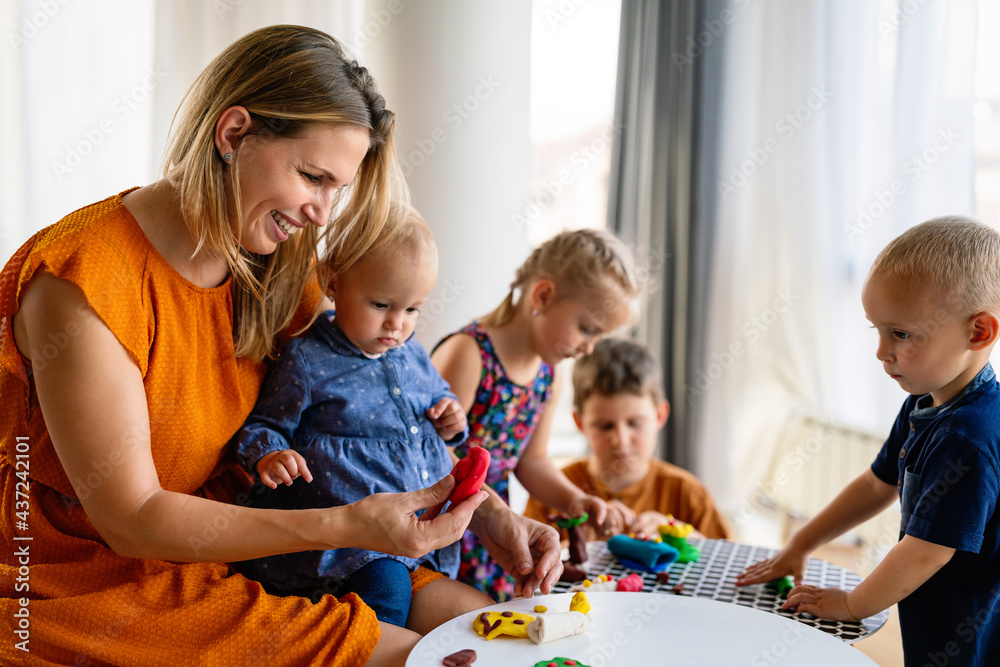 Mother or nursery teacher teaches her children to work with colorful play clay toys Mother or nursery teacher teaches her children to work with colorful play clay toys