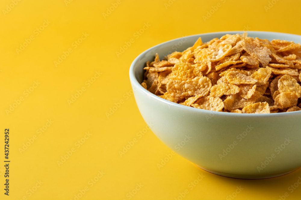 Corn flakes in a blue bowl on yellow background Corn flakes in a blue bowl on yellow background