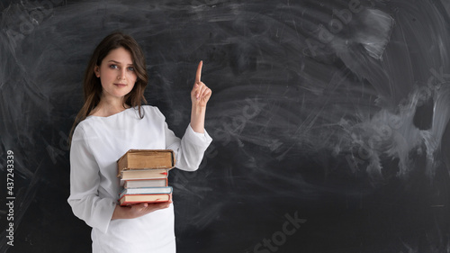Valokuva young beautiful girl student stands against the background of a clean chalk board