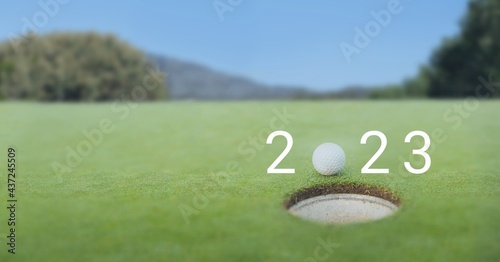 Composition of 2023 number with golf ball by hole on golf course