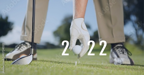 Composition of 2022 number with golf ball placed by golf player on tee on golf course