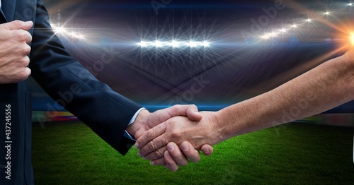 Composition of business people shaking hands over sports stadium