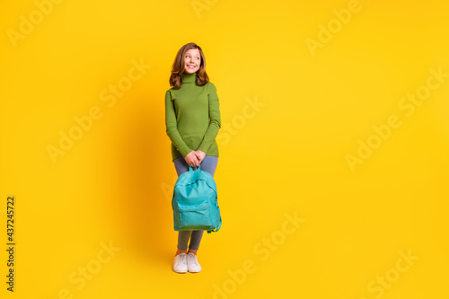 Full length body size photo smiling girl keeping rucksack looking copyspace isolated vivid yellow color background © deagreez