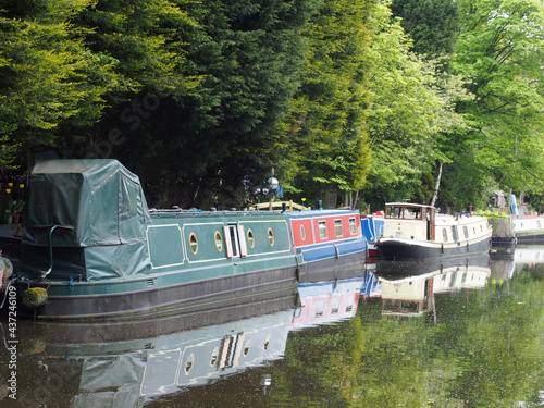 canal boats moored opposite the path on the rochdale canal near hebden bridge surrounded by trees in summer photo