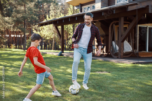 Happy father and son playing football and smiling while having fun on the backyard