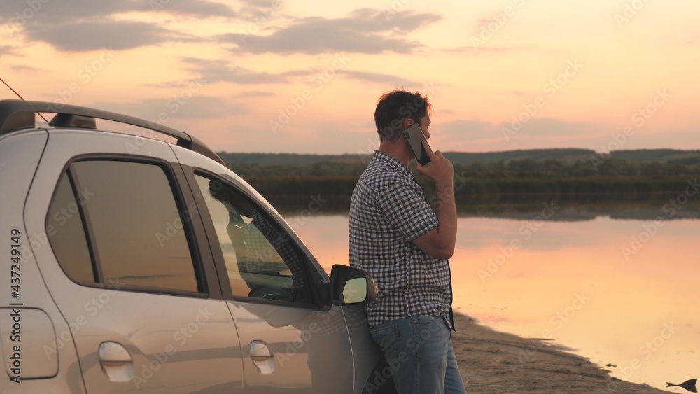 An adult business man talking on the phone at sunset, doing a smartphone conversation on a business trip, making appointments and solving important problems by online negotiations