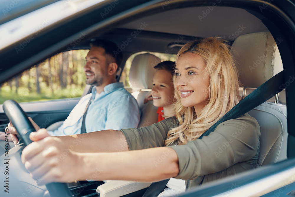 Young beautiful family with little boy  smiling while driving in the car
