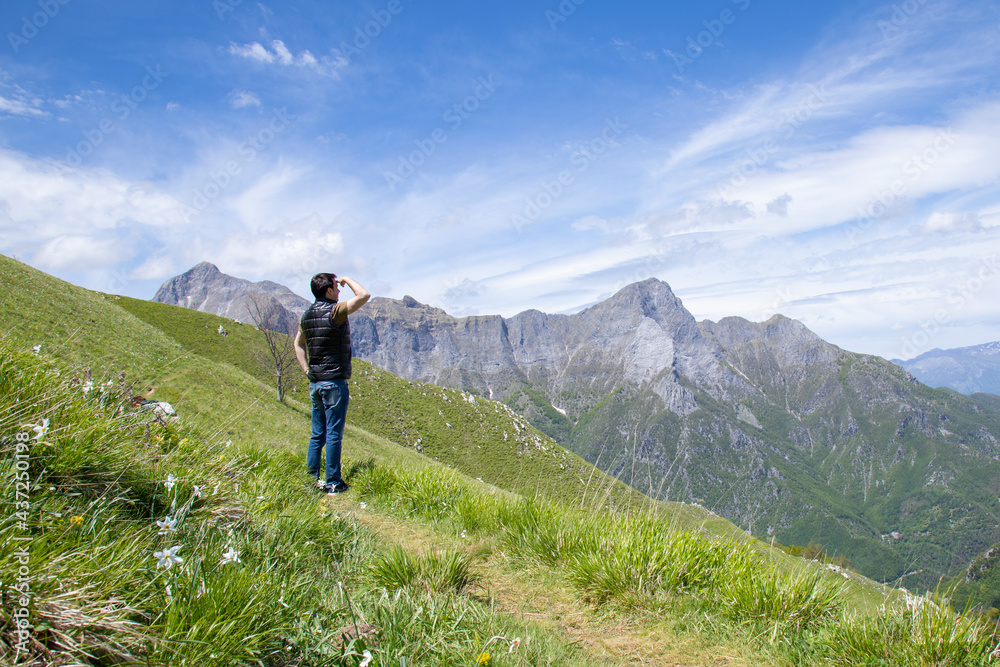 man looks into the distance in flowered mountains of Apuan Alp
