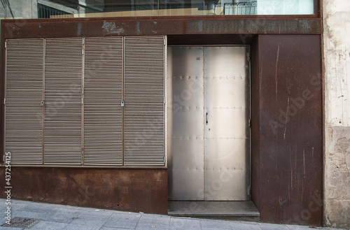 Facade with silver metal door and silver metal window shutters. Brown framing. copy space.