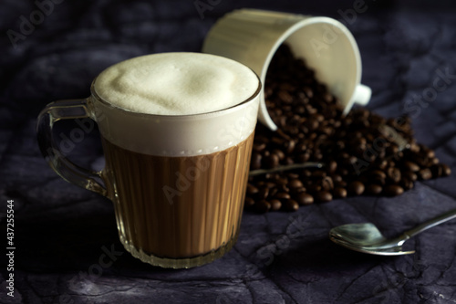 Hot latte with coffee beans on dark stone background