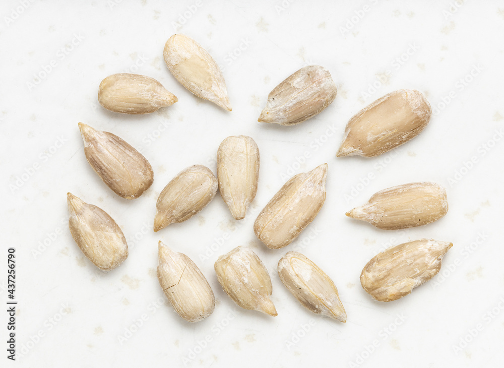 Obraz premium several peeled sunflower seeds close up on gray