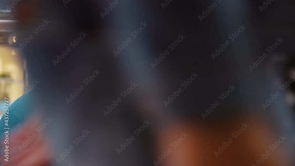 Asian woman with long hair wearing mask sitting on sofa and swiping tablet, shopping bags next to her, blurred people walking on foreground. Female model browsing internet in mall during pandemic Asian woman with long hair wearing mask sitting on sofa and swiping tablet, shopping bags next to her, blurred people walking on foreground. Female model browsing internet in mall during pandemic