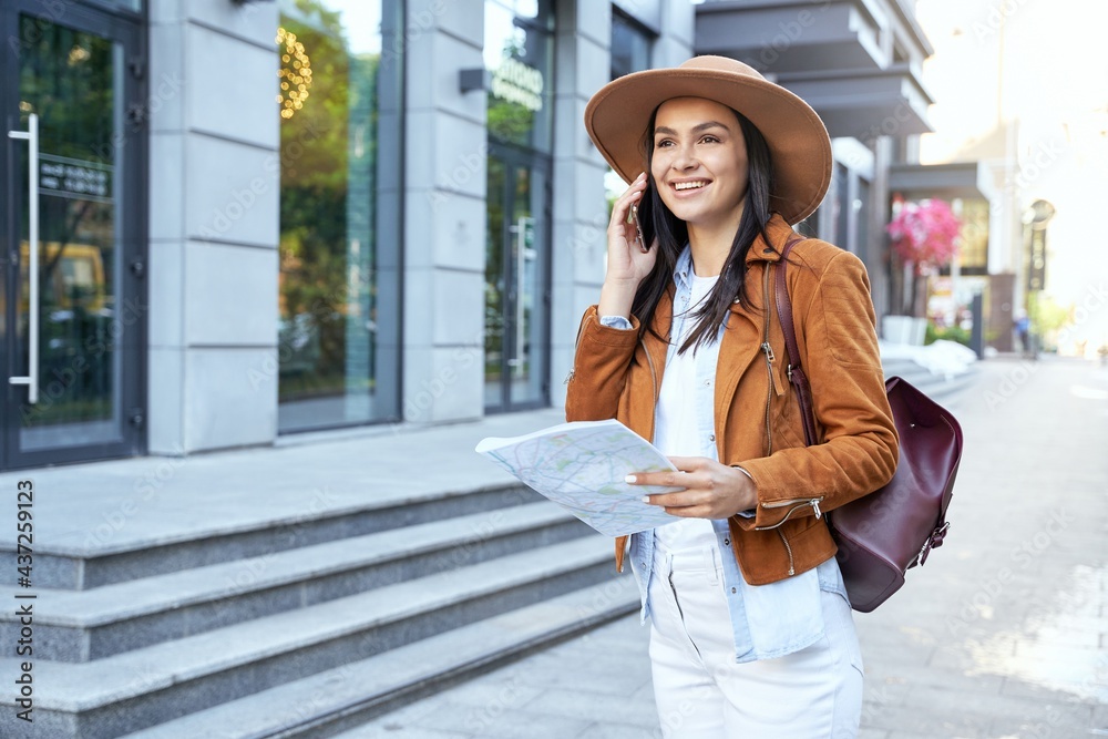 Stylish woman in hat holding map in the city