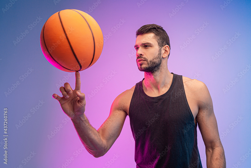 Young sportsman spinning basketball ball on finger