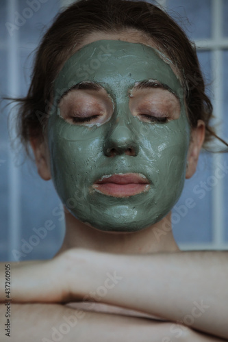 woman with the green clay face mask meditating 