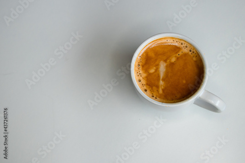 A close up of a white coffee cup with coffee on a white background.