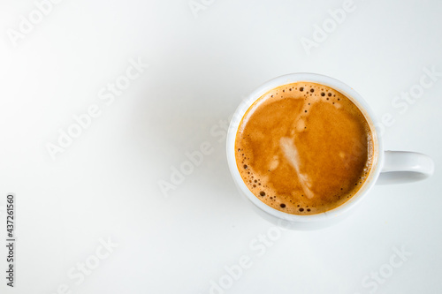 A close up of a white coffee cup with coffee on a white background.