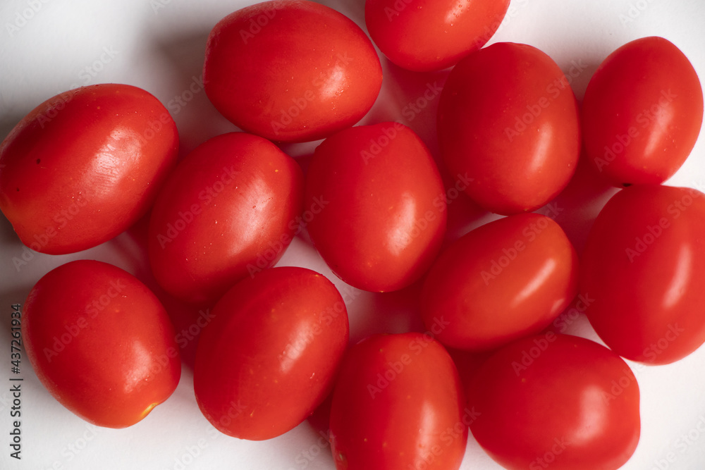 A close up of red cherry tomatoes on a white background. A close up of red cherry tomatoes on a white background.