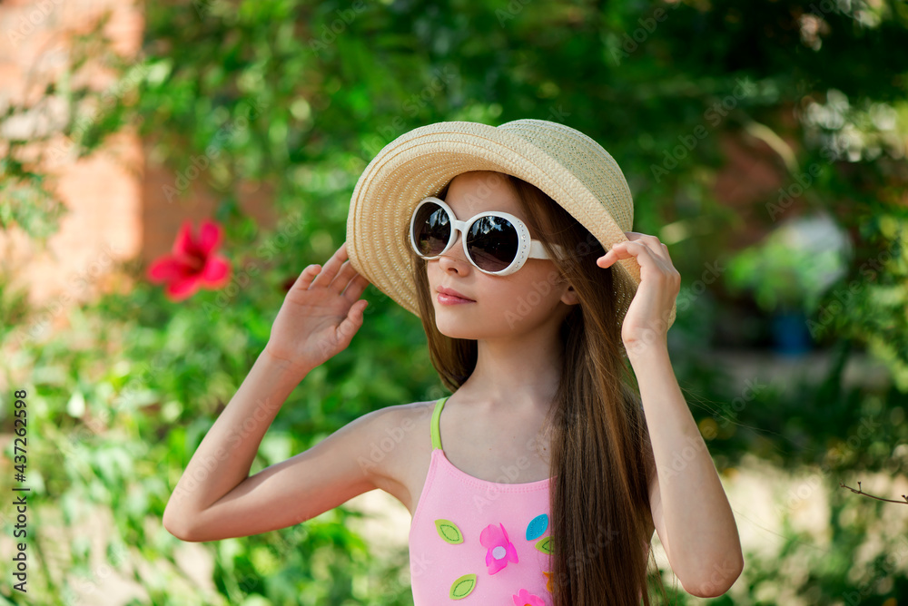 Stylish portrait of smiling girl in hat front of green background. Summer season.