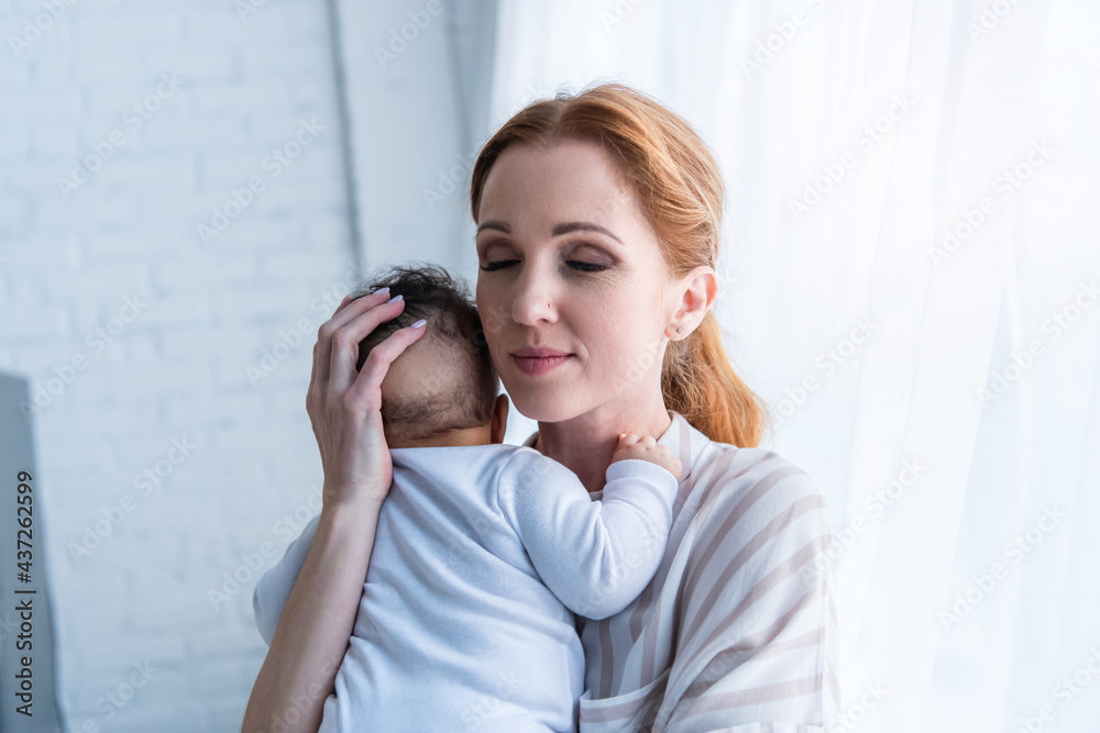 happy woman with closed eyes embracing infant african american child happy woman with closed eyes embracing infant african american child