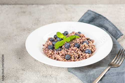 Delicious risotto with blueberries served on lihgt grey concrete table