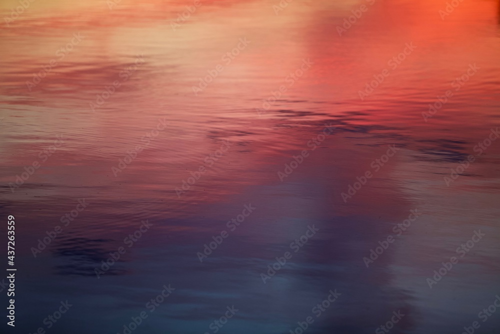 High-contrast shadows and bright reflections on the purple and scarlet surface with violet tints close-up. Bright ripples on colorful smooth water surface close up. Abstract backgrounds and textures. 