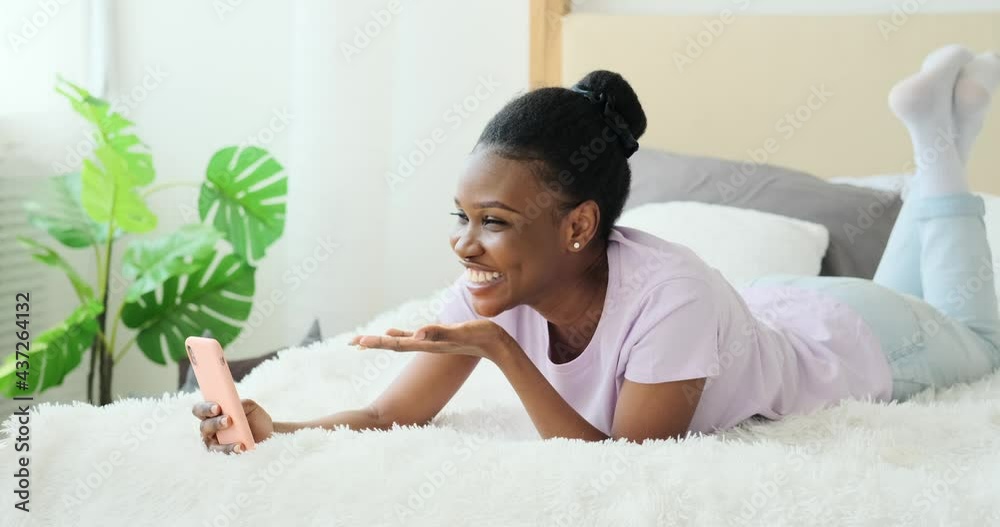 Young woman video chatting using mobile phone in bed at home Young woman video chatting using mobile phone in bed at home