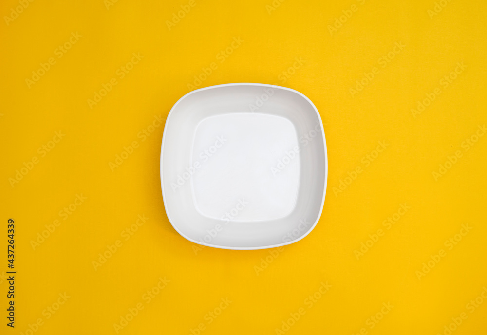 empty white square plate isolated on yellow background. a white plate from the top point of view. a square plate with rounded corners. empty white square plate isolated on yellow background. a white plate from the top point of view. a square plate with rounded corners.