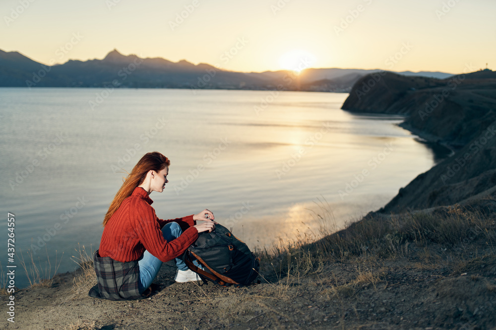 woman on vacation resting in the mountains near the sea at sunset